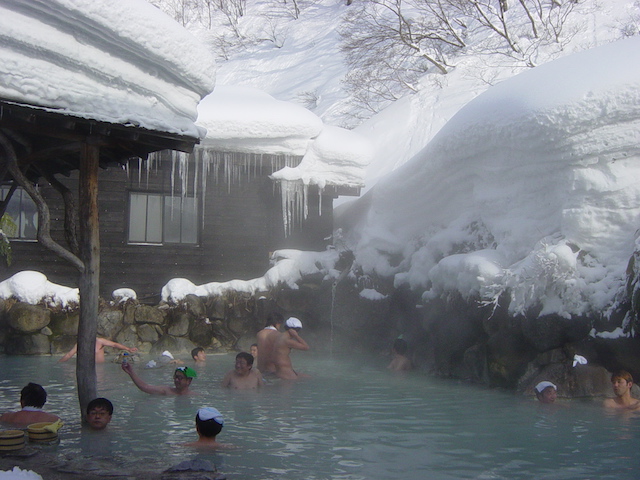 Unter freiem Himmel: Dampf steigt aus dem heißen Wasser eines Bades für Herren auf, Eiszapfen hängen vom Vordach herunter, um das Becken liegt eine dicke Schneeschicht.
