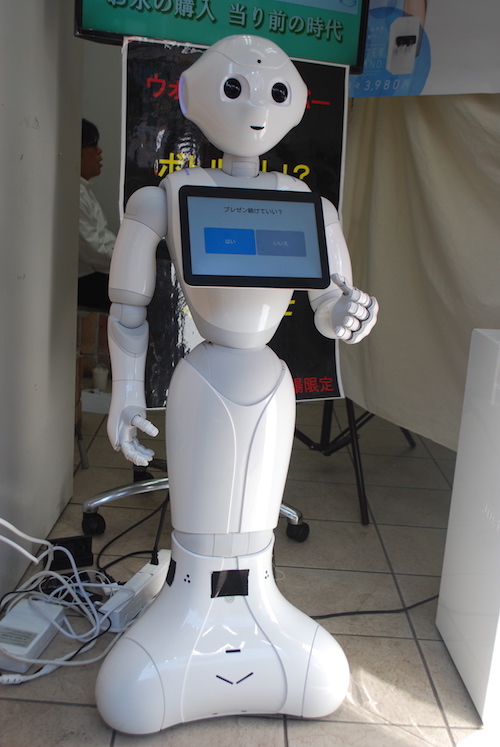 Ein weißer, menschenähnlicher Roboter mit großen schwarzen Augen und einem Bildschirm auf der Brust.