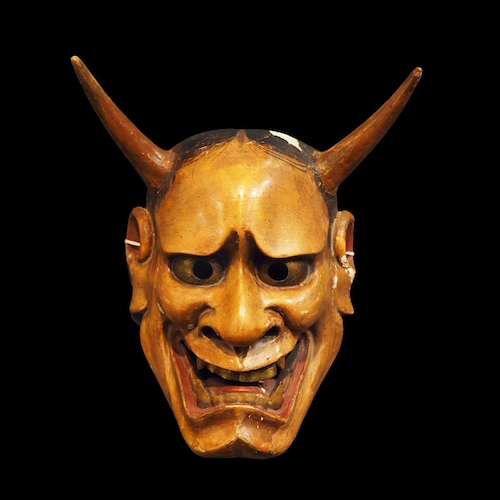 Nō-Maske mit verzerrten Gesichtszügen, zwei Hörner, hervorstechende Augen golden bemalt, aufgerissener Mund