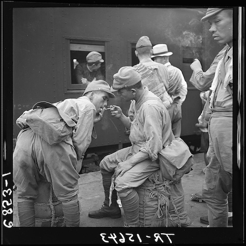Japanische Soldaten am Bahnsteig, einer gibt einem anderen Feuer für die Zigarette