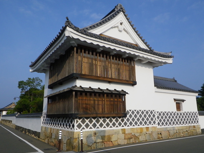 Traditionelles Gebäude mit weißem Verputz und braunen Holzverschlägen.