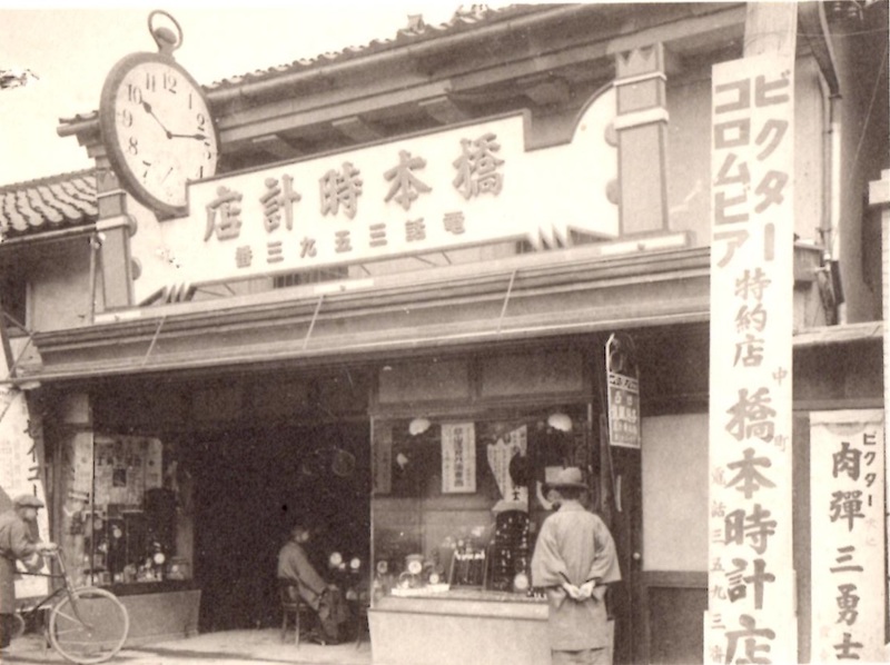 Ladenfront eines Uhrengeschäfts mit einem großen Ziffernblatt.