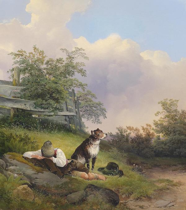 Schlafender junger Mann am Rand eines Wanderweges, sein Hund sitzt neben ihm und hält Wache.