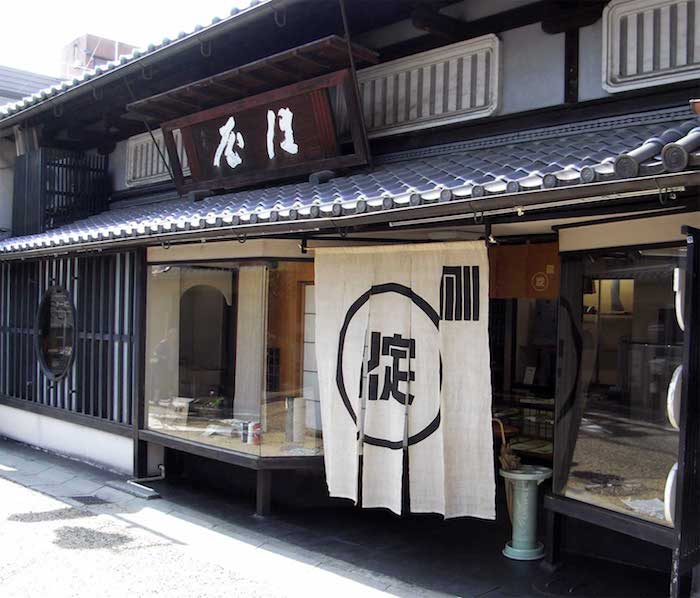 Holzhaus mit Schaufenstern und Vorhang (nori) am Eingang.