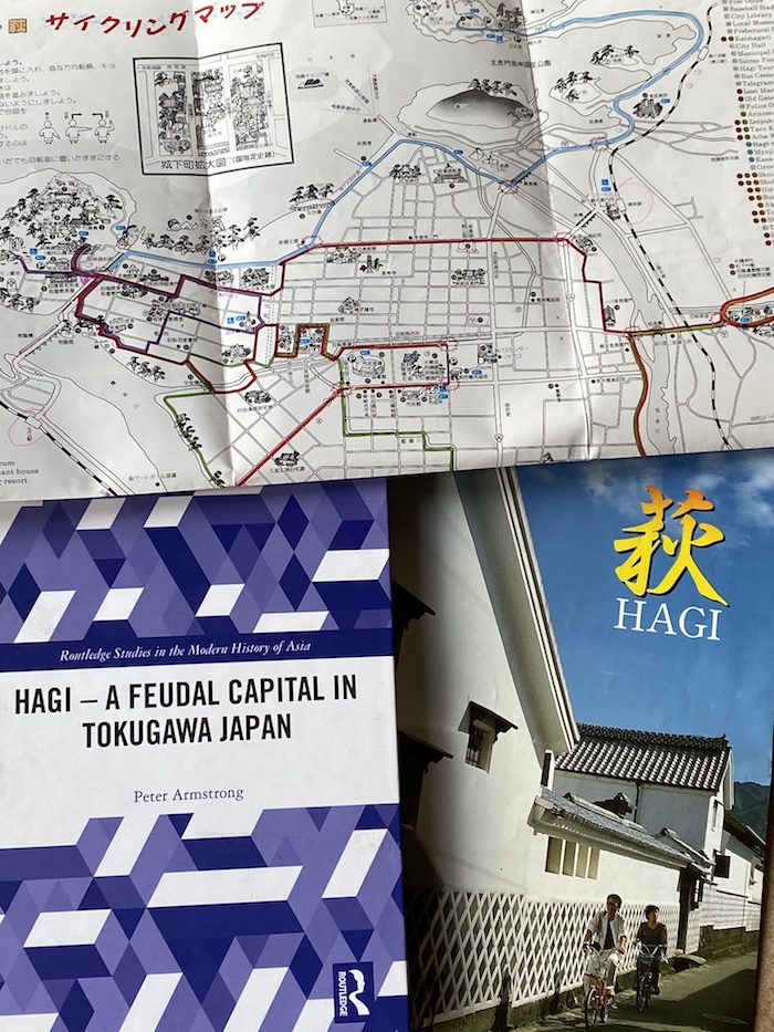 Das Buch "Hagi" neben einem Werbeprospekt für die Stadt und einem Stadtplan mit einer Fahrradroute