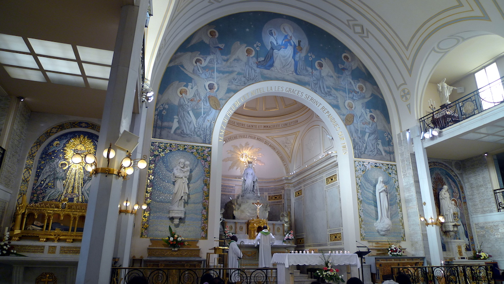 Heller Altarraum einer Kapelle in Weiß und Hellblau, im Zentrum eine Marienfigur.