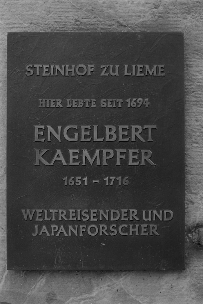 Schwarze Platte mit grauen Buchstaben: „Steinhof zu Lieme / Hier lebte seit 1694 / Engelbert Kaempfer / 1651-1716 / Weltreisender und Japanforscher“