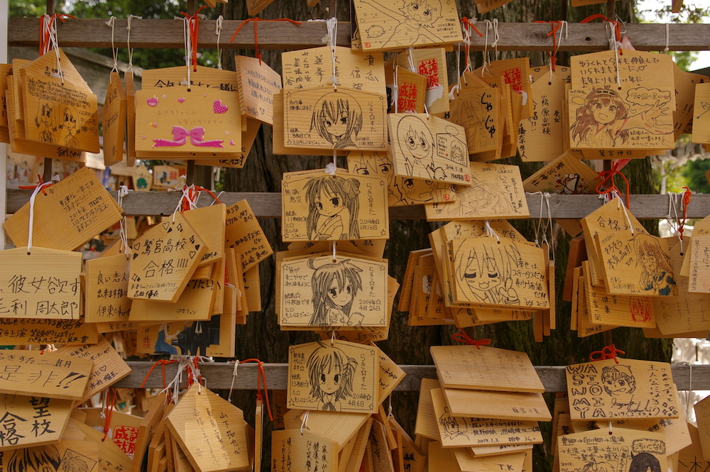 Mit Manga-Figuren bedruckte Holztäfelchen, die beschriftet und aufgehängt wurden.