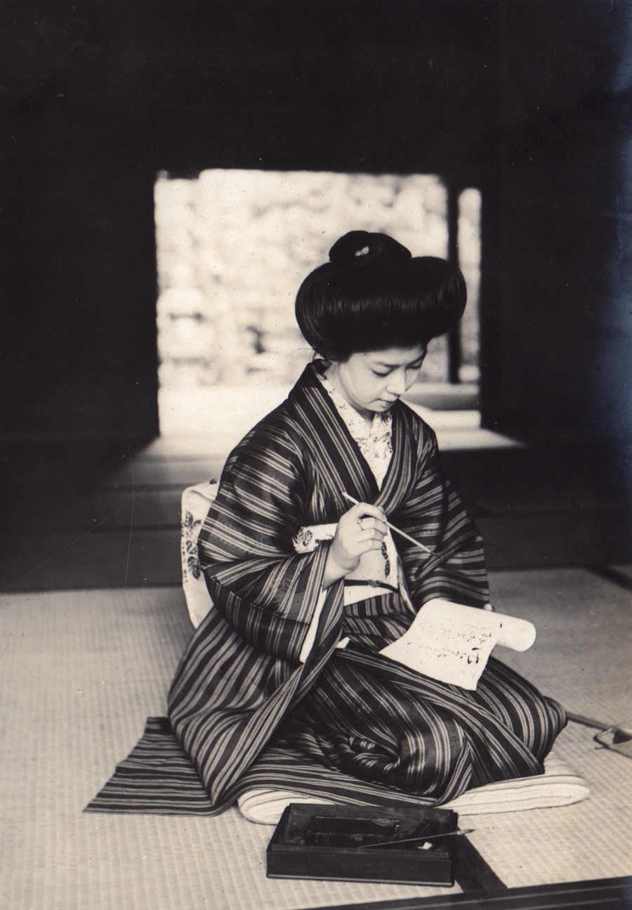 Foto von einer Frau, die am Boden kniet und einen Brief schreibt.