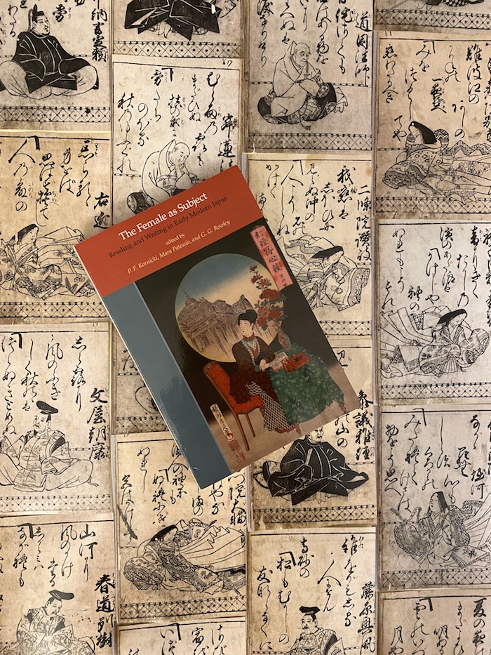 Das Buch, das empfohlen wird, liegt vor vielen Buchseiten einer historischen Ausgabe von "Hyakunin isshu"