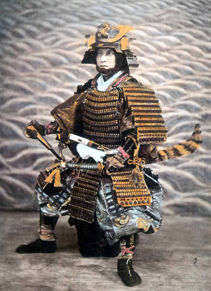 Mann in Samurai-Rüstung, sitzend.