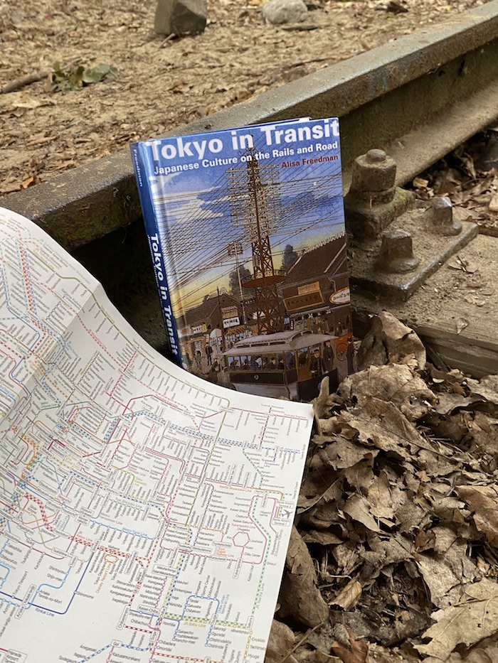Das Buch gemeinsam mit einem Plan des Tokyoter Bahnnetzes auf einer Schiene platziert.