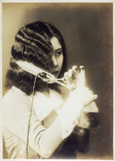MOga: Schwarzweiß-Foto von einer Japanerin, die sich mit einem Lockenstab das Haar wellt