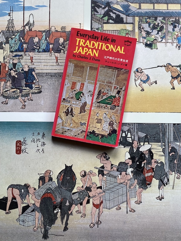 Das Buch eingewickelt in ein braunes Furoshiki-Tuch, so dass der Titel noch lesbar ist.